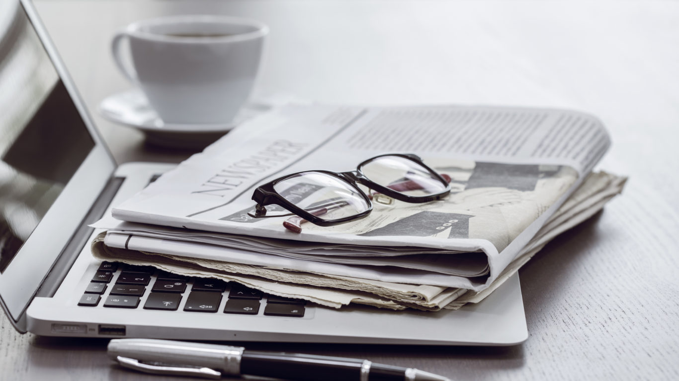 Newspaper with computer on table