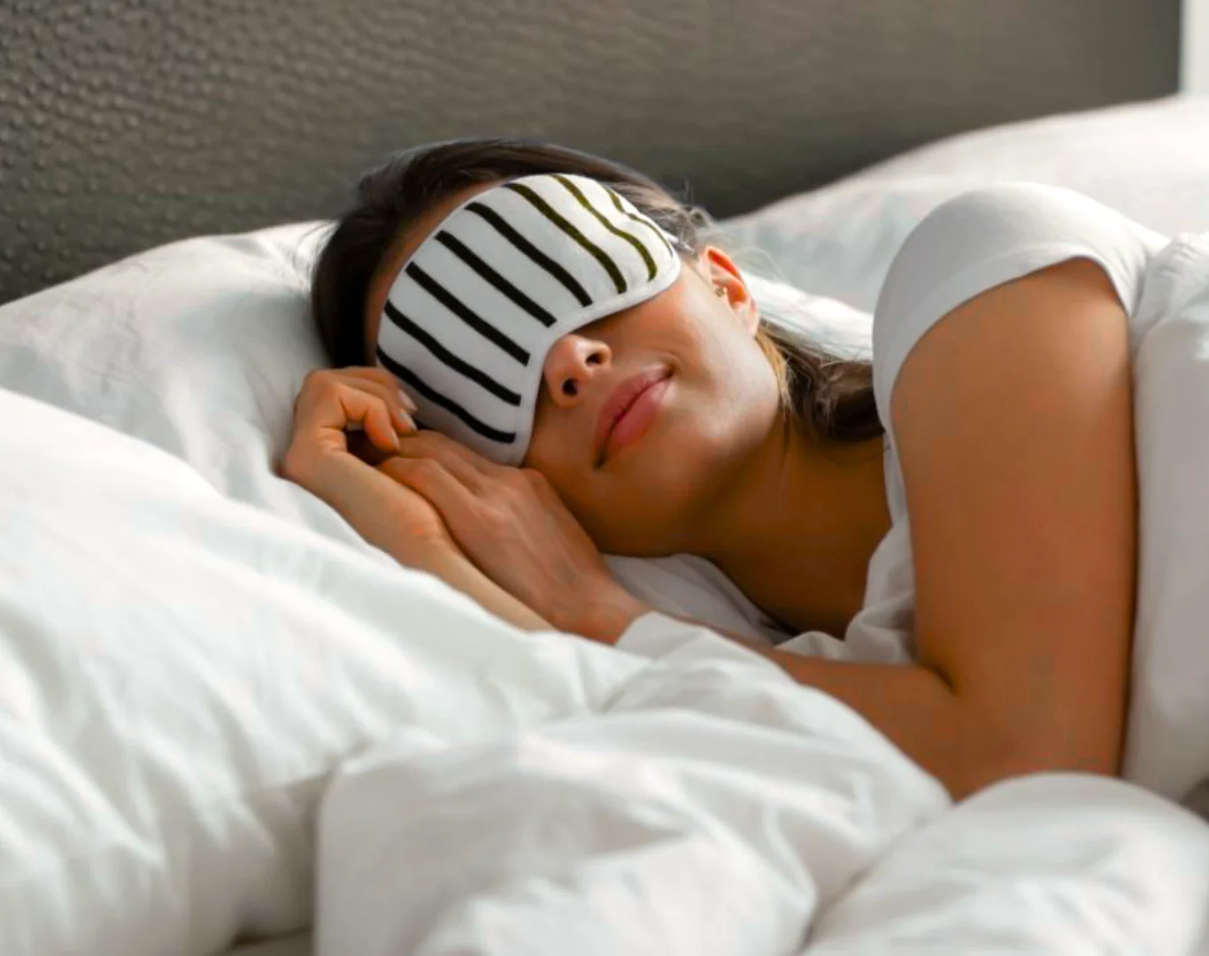 Guest enjoying restful sleep in plush hotel bed with soft pillows and luxurious linens for a comfortable stay.