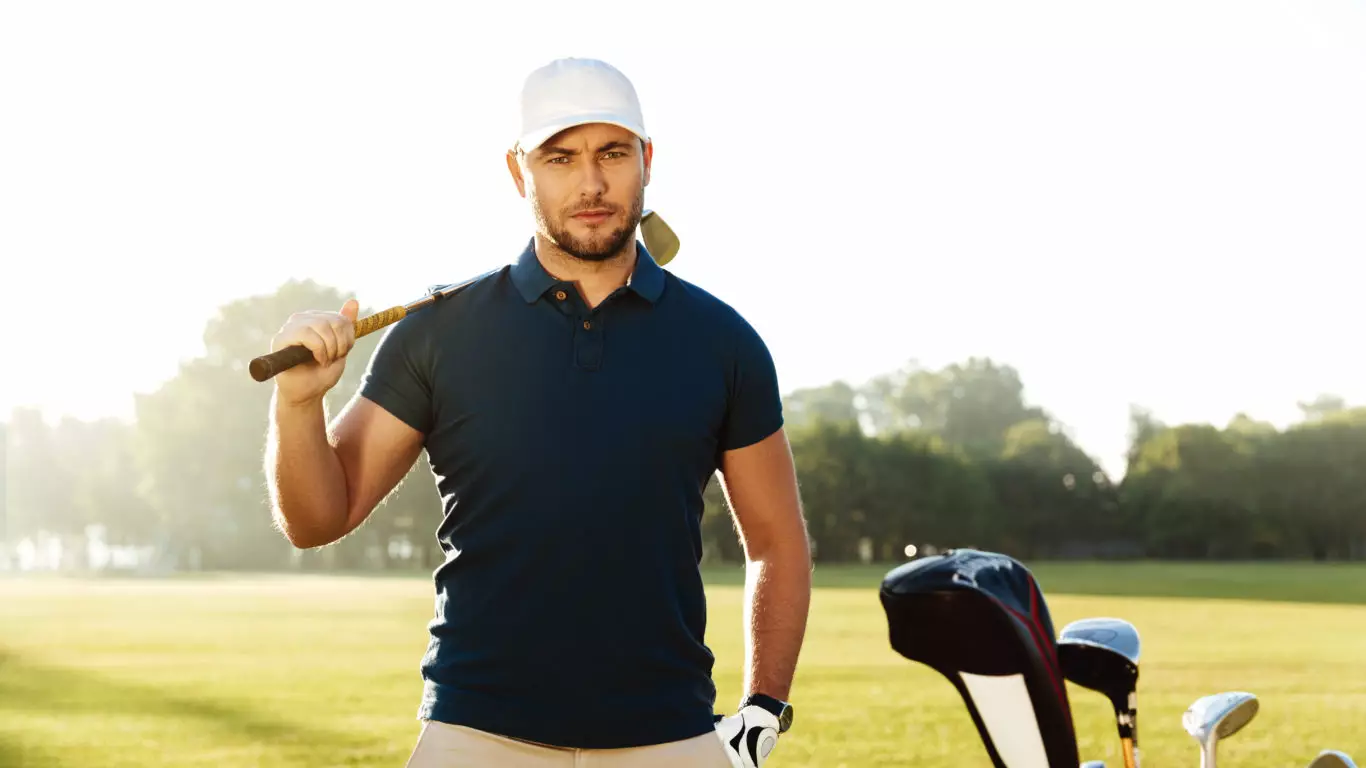 Handsome confident male golfer standing with golf club