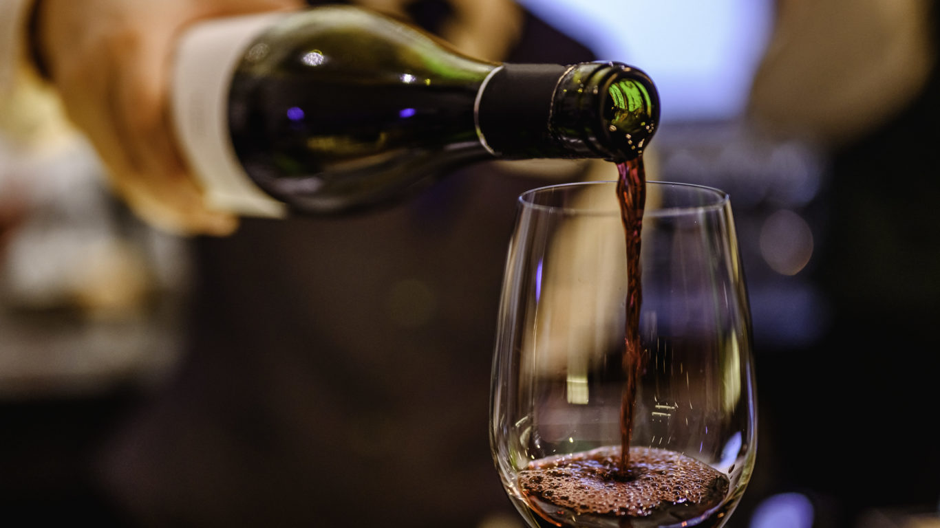 Pouring glass of red wine from a bottle.