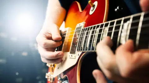 man playing on guitar close up view