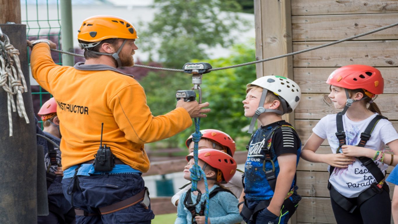 Guests enjoy exciting zipline activity, guided by an instructor, amidst lush green scenery for an adventurous hotel experience.