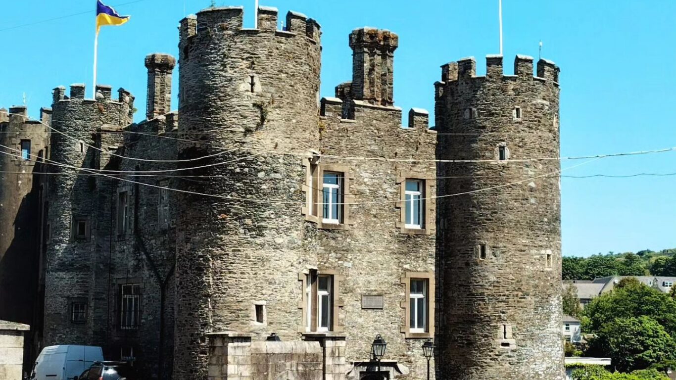 Historic castle hotel entrance with stone towers, flags flying, and scenic views promising a unique stay experience.