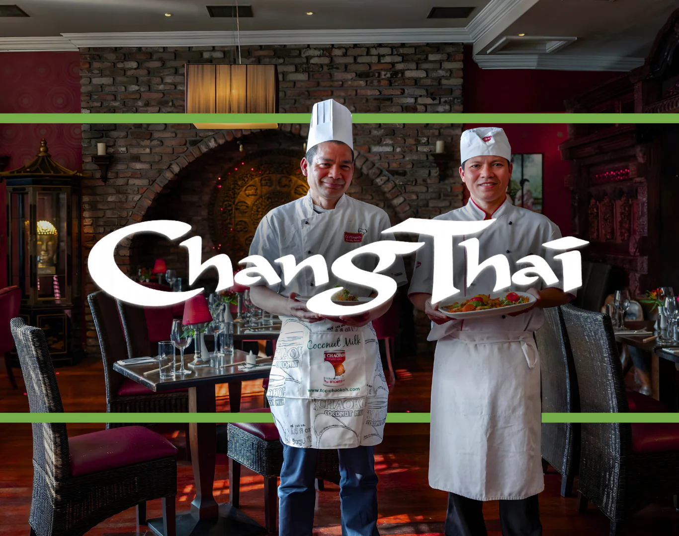 Chefs holding Thai dishes in elegant, warmly lit restaurant with brick wall and ornate decor, inviting guests for fine dining.