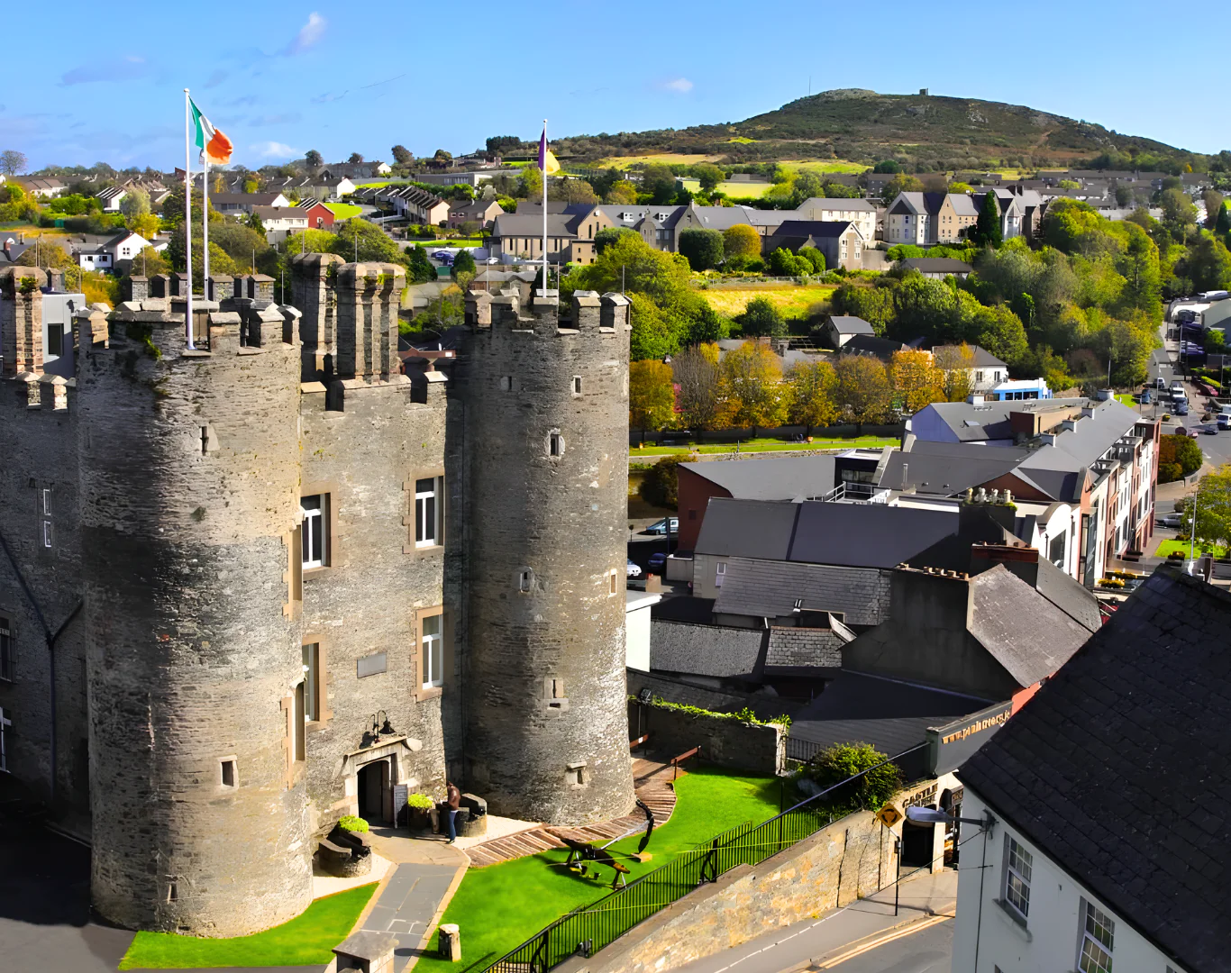 Majestic castle hotel with lush gardens, offering breathtaking hill views and charming village experience in serene surroundings.