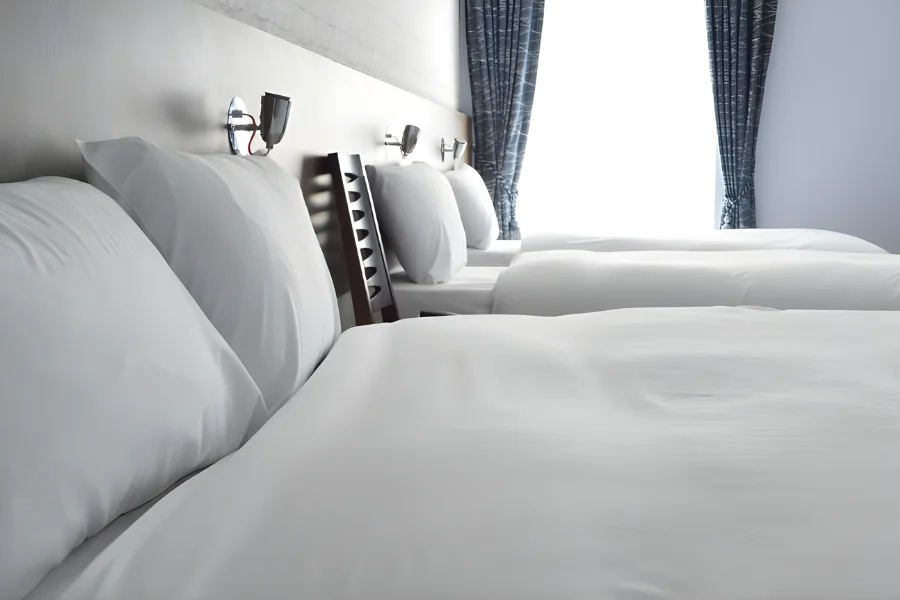 Spacious twin hotel room with elegant blue curtains and modern bedside lighting for a relaxing stay.