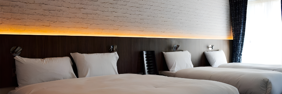 Modern hotel room with three cosy beds, soft lighting, and sleek decor, promising a comfortable stay near local attractions.