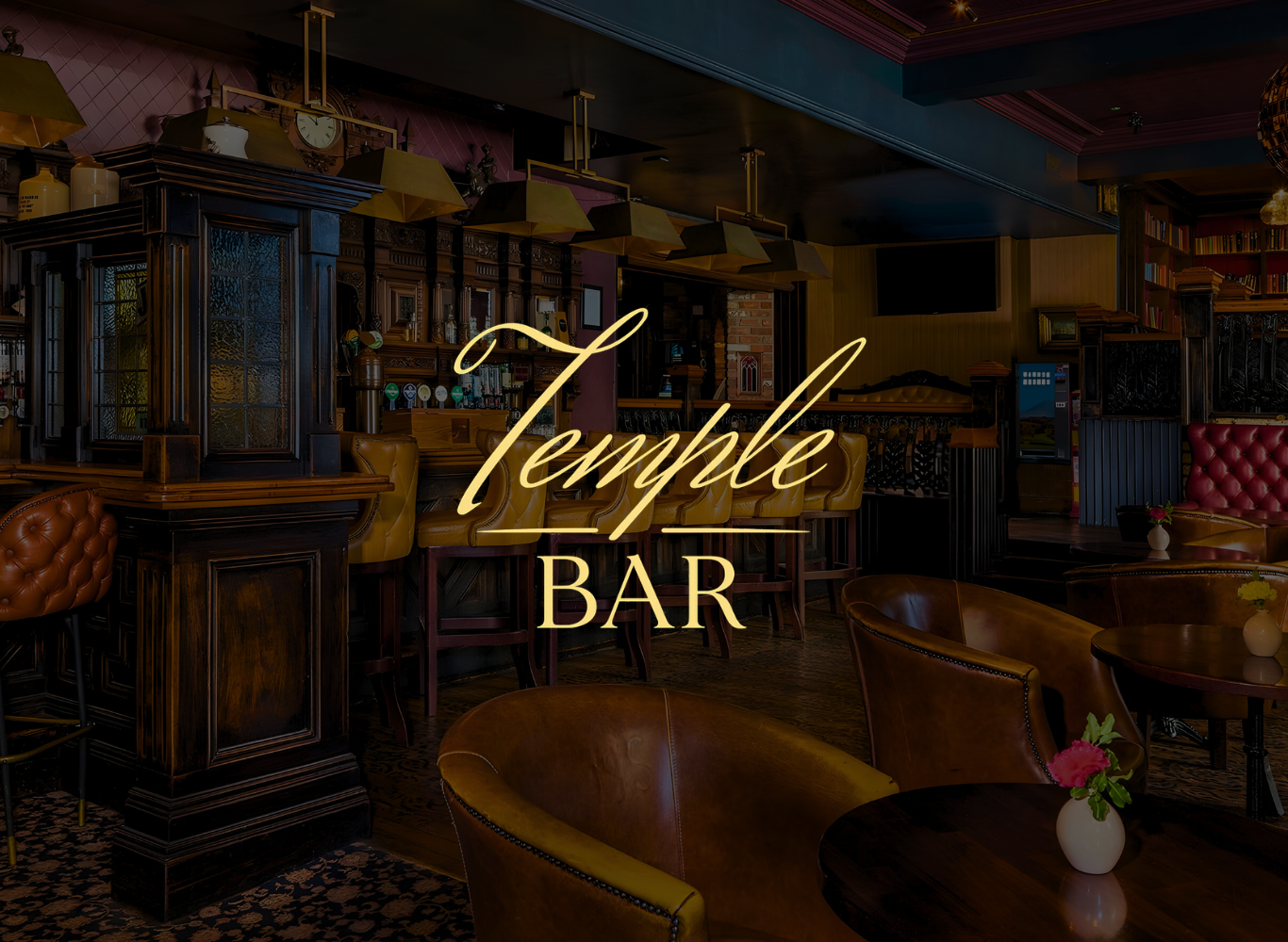 Cosy hotel bar with rich wood decor, leather seating, ambient lighting, and flowers on tables for a relaxing experience.